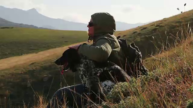 一个女人带着一只狗坐在山坡上视频下载