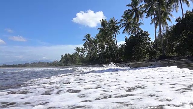 慢镜头:泡沫的海浪，空荡荡的热带沙滩和巴厘岛的棕榈树视频下载