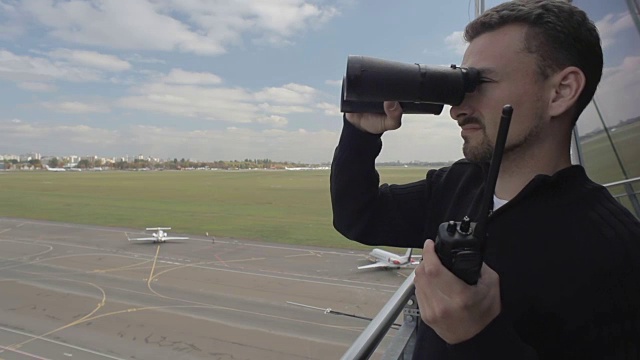 机场工作人员在管制塔台使用双筒望远镜和便携式无线电视频下载