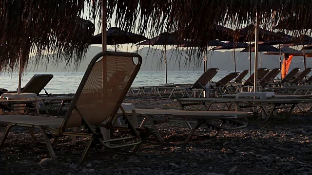 海岸边的茅草伞和躺椅的剪影视频素材