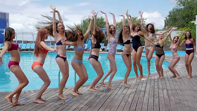 在泳池边有乐趣，一群女人在度假村，游泳池派对，苗条的女孩在泳衣视频素材