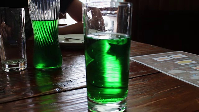 在一家咖啡馆的桌子上，绿色的柠檬水在杯子里冒泡视频素材