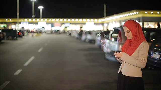 阿拉伯妇女晚上在街上使用手机视频素材