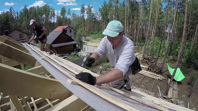 屋顶工人正在把钉子钉进屋顶的木板里。视频下载