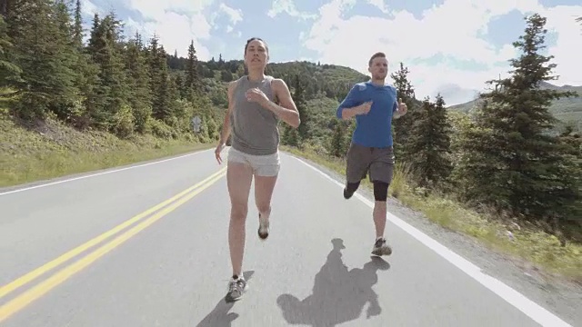 迷人的跨种族夫妇在山间风景优美的高速公路上跑步视频下载