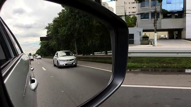在高速公路上开车时透过后视镜看视频素材