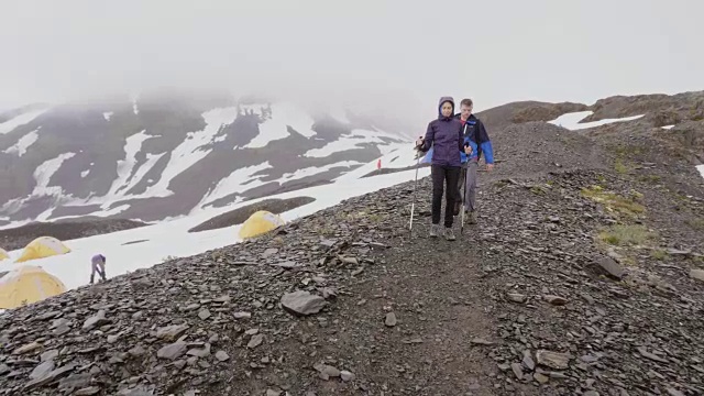 跨种族的年轻夫妇沿着阿拉斯加的冰川背包旅行视频素材