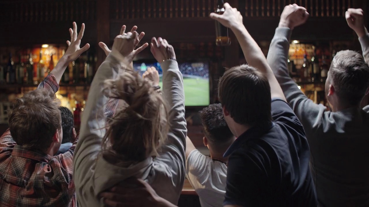 一群体育迷在酒吧里看足球视频素材