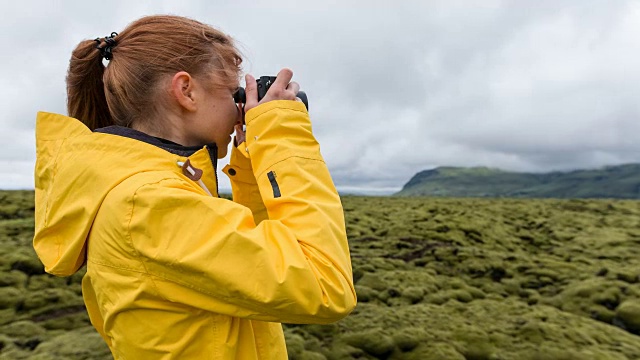 身穿黄色雨衣的游客在冰岛拍摄绿色和苔藓景观视频素材