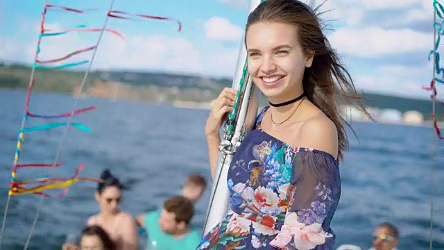 一个快乐的年轻女子在游艇上的肖像，在一个温暖的日子里，一艘船在海上航行，女士是快乐的，笑着，在她的手中的太阳镜视频下载
