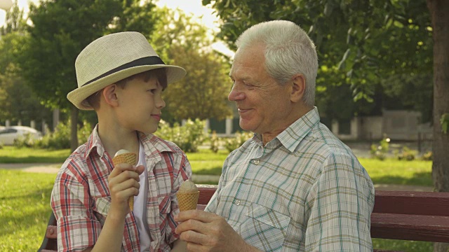 老人和他的孙子在长凳上吃冰淇淋视频素材