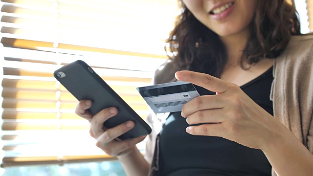 购物女人拿着智能手机和信用卡进行网上购物视频素材