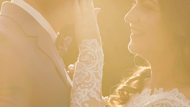 温柔的新婚夫妇拥抱和爱抚在金色的阳光户外视频下载