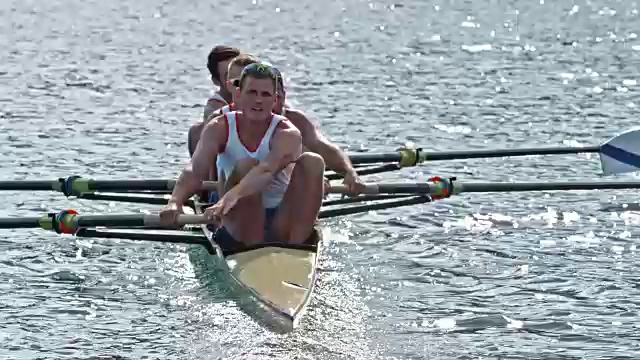 四个运动员在阳光下在湖中划船视频素材