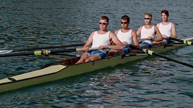 男运动员们在阳光下划船横渡湖面视频素材