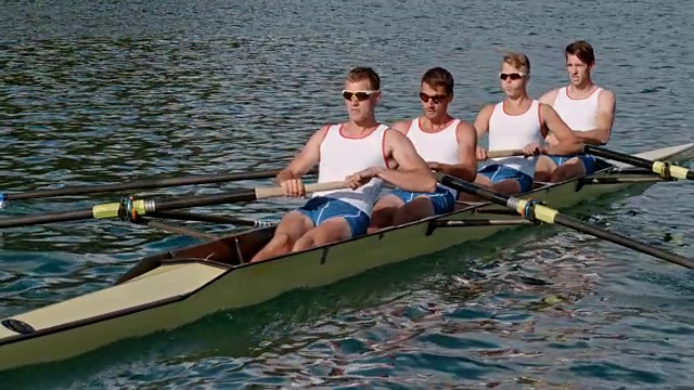 在一个阳光明媚的早晨，四名男运动员划着船横渡一个湖视频素材