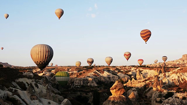 在卡帕多西亚，热气球飞过童话般的烟囱，背景是乌奇萨城堡视频素材