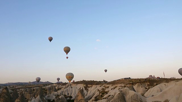 在卡帕多西亚的乌奇萨尔城堡的背景下，热气球正飞过精灵烟囱视频下载