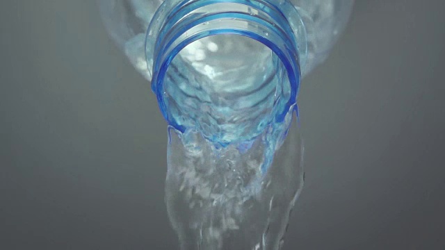 慢动作:特写水从塑料瓶与灰色背景视频下载