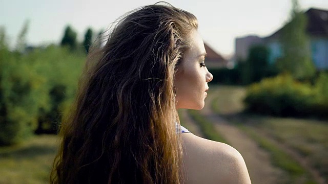 一个忧伤的漂亮女人，一头棕色的长卷发，正在田野上散步，一边看着一边等着有人视频素材
