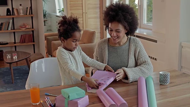 创造性的非洲裔美国母亲和女儿有乐趣，而包装礼盒在家里。视频素材