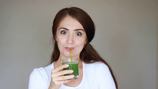 蔬菜排毒清洗奶昔。女孩微笑着喝着绿色果汁。饮食和健康的生活方式视频素材