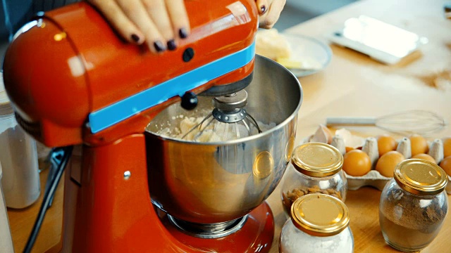 年轻女性在碗里准备面团的特写镜头。女人打开搅拌机，把原料混合在一起视频素材