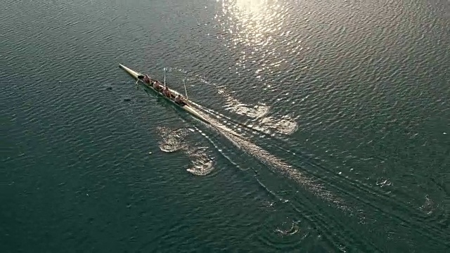 在一个阳光明媚的日子里，跟随四名无舵手滑过湖面的运动员视频素材