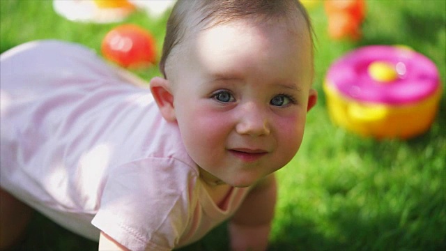 有趣和可爱的婴儿爬行的腿和手在绿色的草地在夏天视频下载