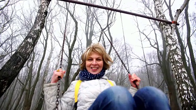 快乐、美丽、活跃、有吸引力的50岁成熟女人在公园的秋千上荡秋千视频下载