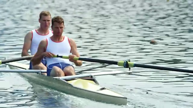 两名男运动员划着一组无舵手的划艇横渡湖面视频素材