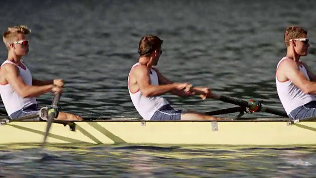 男运动员在阳光下与他的团队在一个没有舵手的四人赛艇视频素材