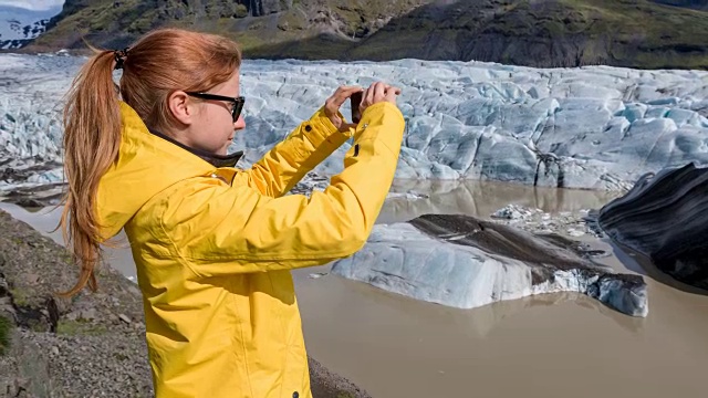 穿着黄色雨衣的游客在冰川上拍照视频下载