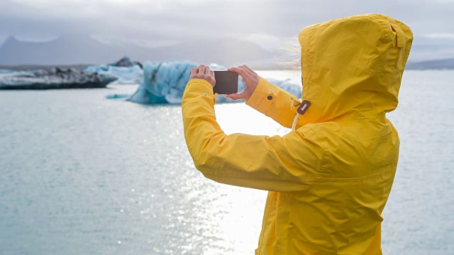 一名女子在冰川湖中拍摄冰山的照片视频下载
