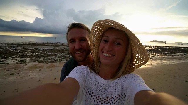 日落时分，一对年轻夫妇在海滩上自拍视频素材