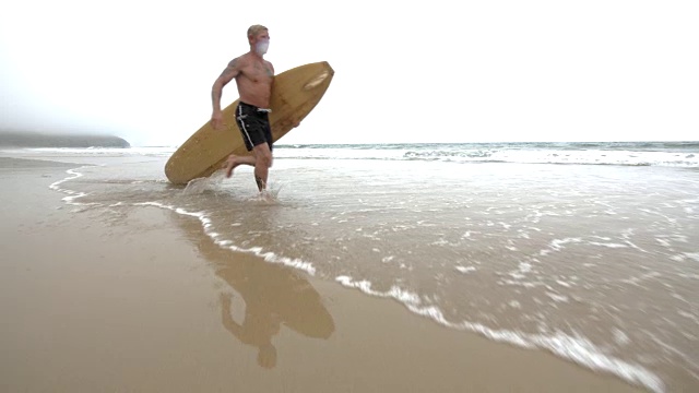 一个成熟的冲浪者走向海洋。视频素材