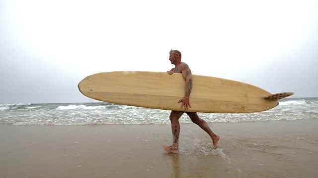 一个成熟的男性冲浪者用他的长板在冲浪。视频素材