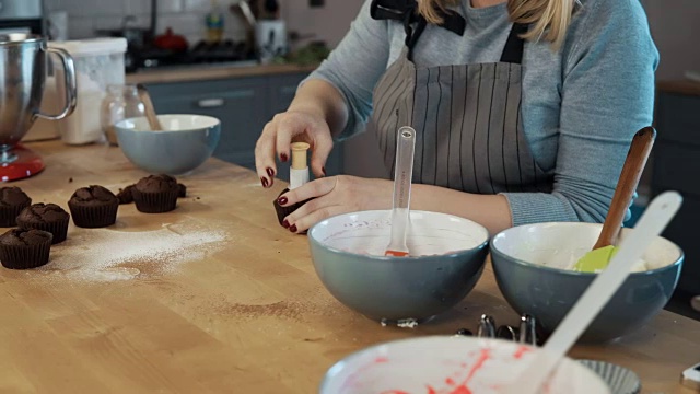 年轻的金发女人在厨房做纸杯蛋糕。美丽的女性用切割机做松饼视频素材