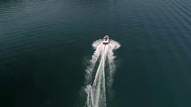 无人机滑水天线在美丽的碧水上拉人的船上空飞行视频素材