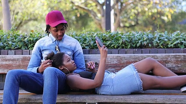 非洲夫妇在公园里放松，用手机视频下载