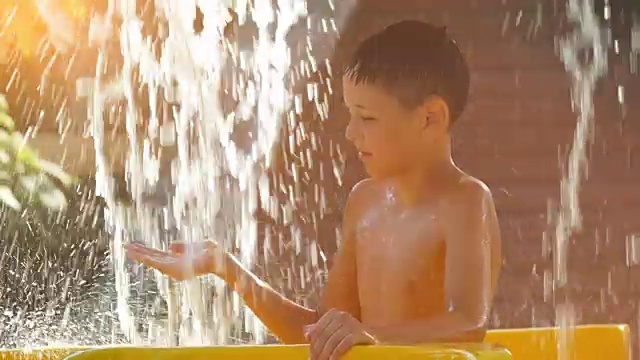 炎炎夏日，男孩在水上公园的瀑布下凉爽凉爽视频素材