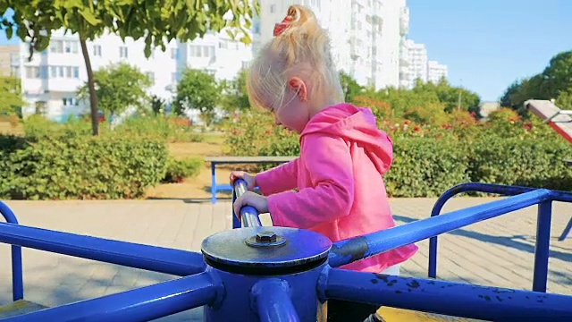 慢镜头:在城市公园里荡秋千的三年快乐女孩。视频素材