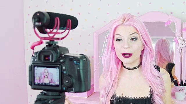 一个染成粉红色头发的年轻女子在卧室里对着摄像机说话视频素材