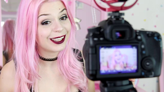 染成粉红色头发的年轻女子在社交媒体上拍摄自己视频素材