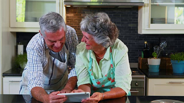 高级夫妇在厨房里使用数码平板电脑4k视频素材