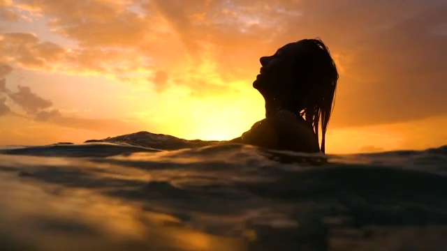性感的女孩与湿漉漉的头发和嘴唇在日落在水下的水视频下载
