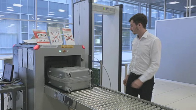 商人在机场等待通过x光扫描仪扫描行李视频素材