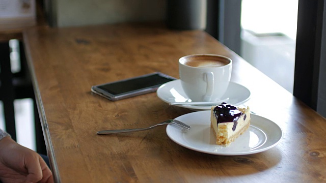女人手切蓝莓奶酪派和咖啡在休息时间，咖啡馆，摄影视频素材