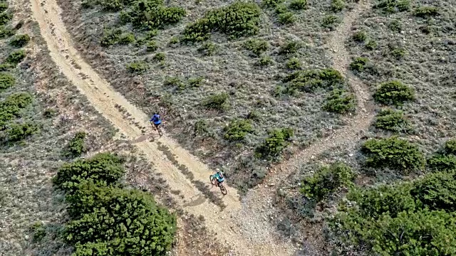 一男一女山地自行车手在阳光下的砾石山路上骑行视频下载
