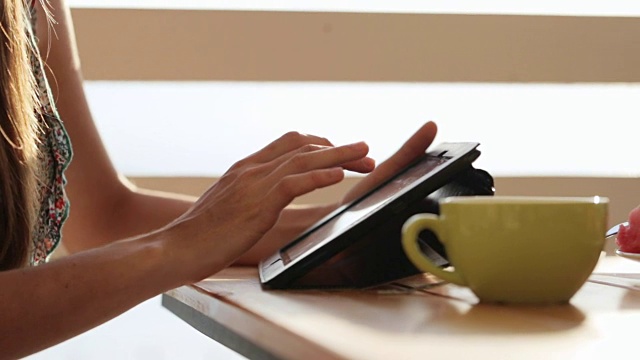 特写女性的手使用平板在露天咖啡馆。视频下载
